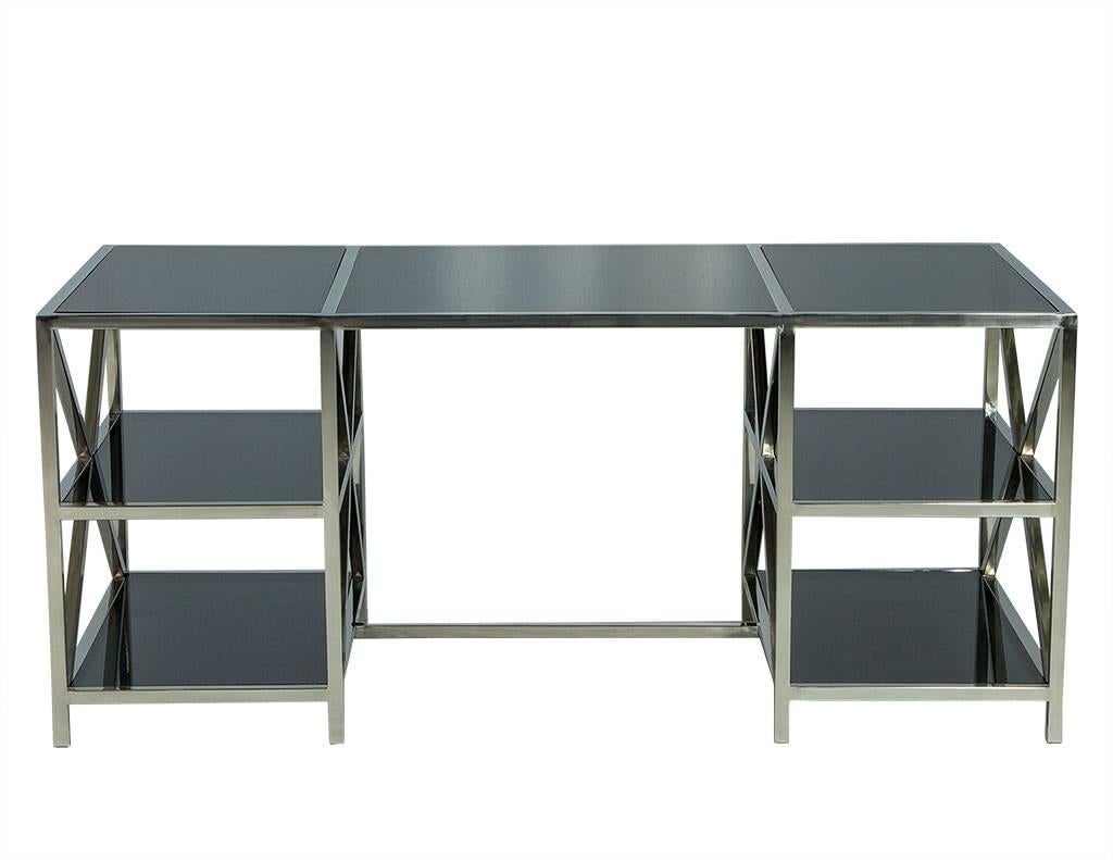 This modern desk is sleek and sophisticated. Composed of a polished stainless steel, X-base frame and divided into two separate shelving units on each side and topped with smoked glass. This piece is sure to add an air of luxury to any office.