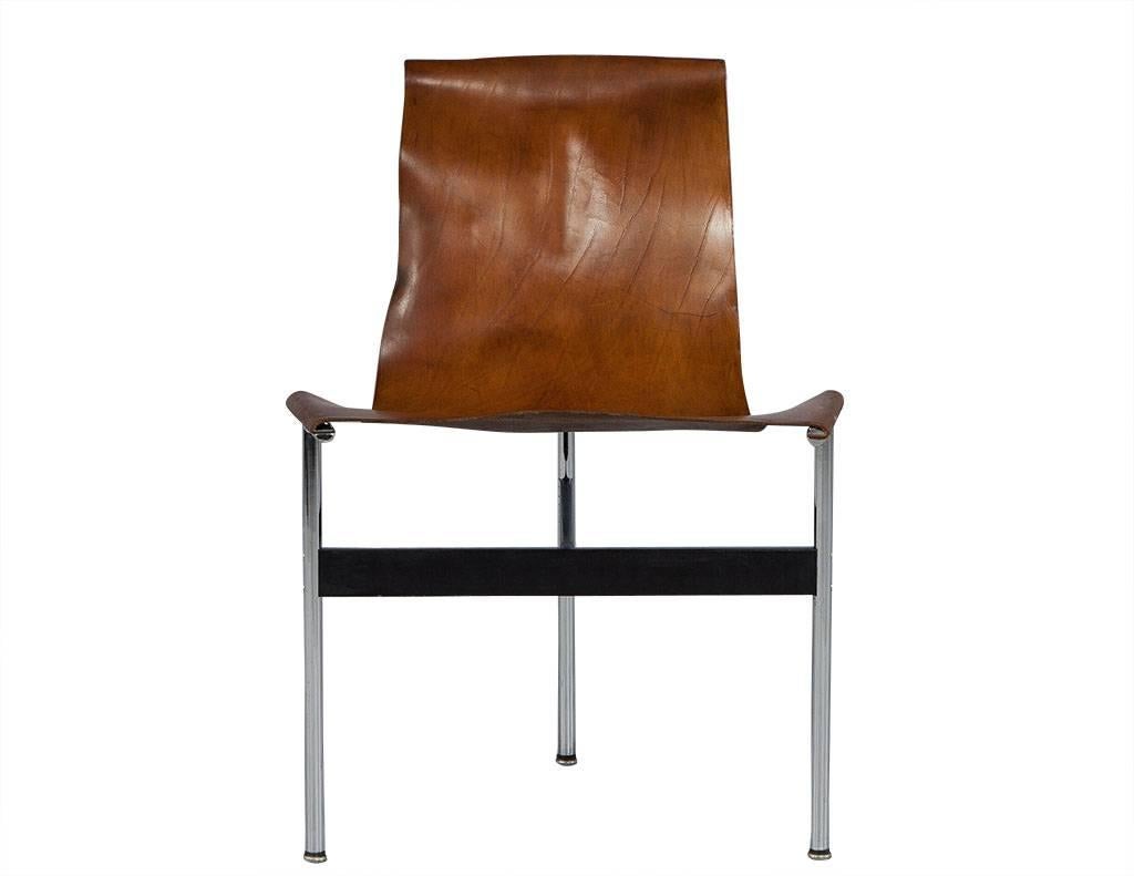 These Mid-Century Modern T-chairs are a picture-perfect combination of rustic texture and modern flair. They are each composed of cognac colored saddle leather slung across a T-shaped tubular steel frame with a T-shaped connector between the three