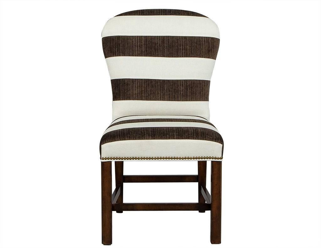 These parson chairs are timeless. Each is upholstered in a Classic dark brown and white thick-striped fabric with rounded edges on the seat back. To add some extra design flair, they are then adorned with an antique brass nailhead trim along the