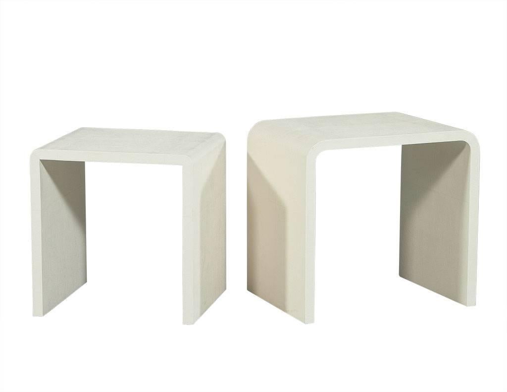 These modern nesting end tables are clean and fun. They are crafted in a waterfall style and wrapped in a cream-colored faux shagreen. A cool set, perfect for a daring living space.

Listing includes two end tables as seen.

Measures: Large