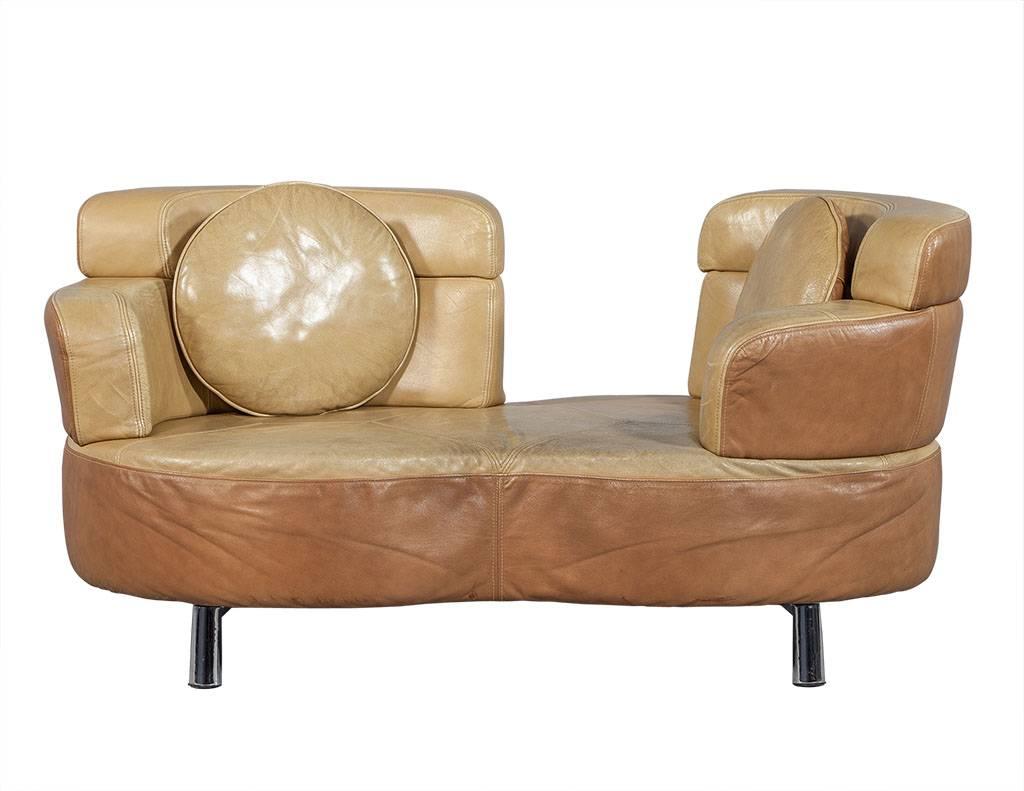 This Mid-Century Modern sitting set includes a two seat loveseat upholstered in a contrasting tan and warm brown leather with a scalloped edge atop surprising chrome feet. The curved end sections rotate to a chaise longue position and both the back