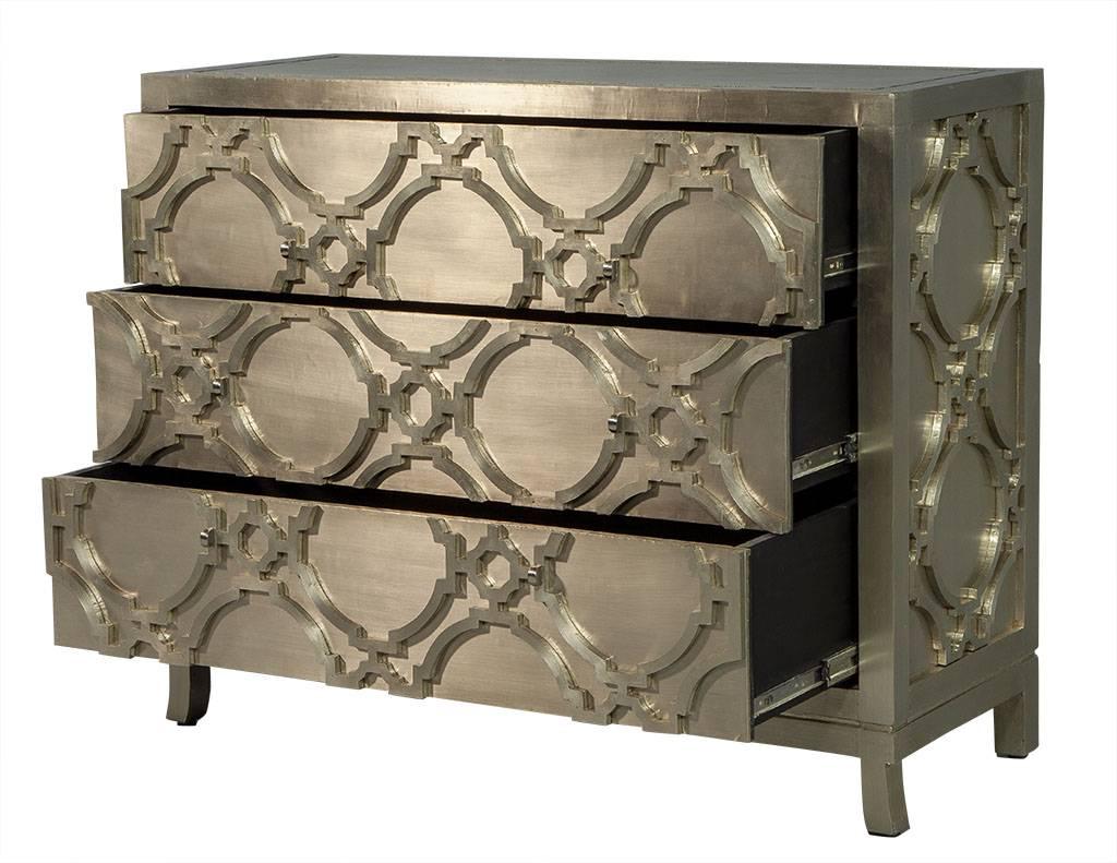 This traditional style chest of drawers is designed by Bernhardt. A gorgeous piece crafted out of a wood case wrapped in German Silver. It contains three front-facing drawers and a decorative trellis pattern on the front and side panels. A truly