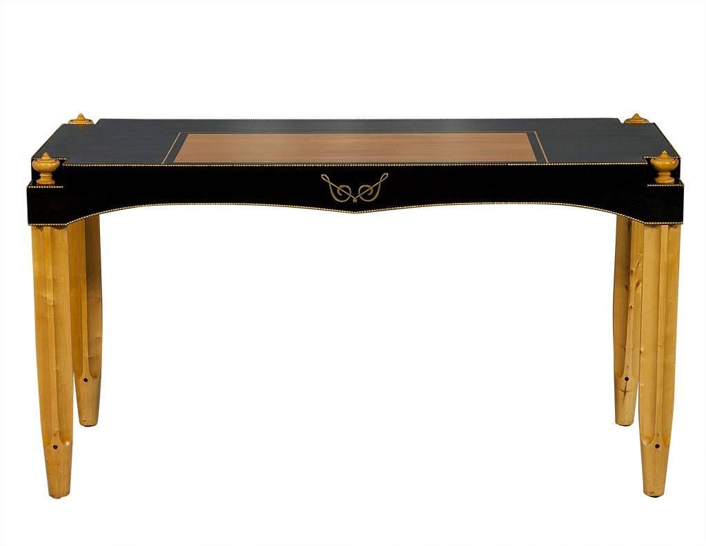 This Art Deco style desk is a real masterpiece! It is comprised of ebonized wood on the top surface with an inset blonde Sycamore wood writing area, gold ball detailing around the edge and wooden finials at the corners. The brass treble clef design