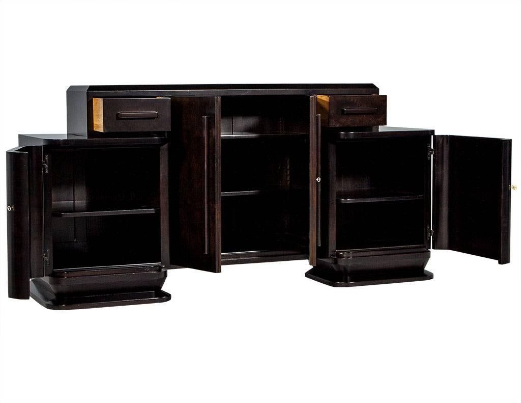 This Art Deco style buffet is striking. It has tons of aged charm, yet has been restored and refinished by Carrocel in a deep, dark brown stain. The raised central compartment has two large centre doors and three shelves inside. The right and left
