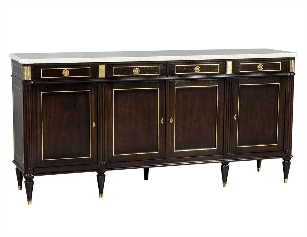 Elegant French buffet, with a thick ivory and grey vein marble top. Solid wood piece finished in black lacquer, with intricate designed brass trim inset around the drawers and doors. Features four top, velvet lined drawers and four bottom doors with