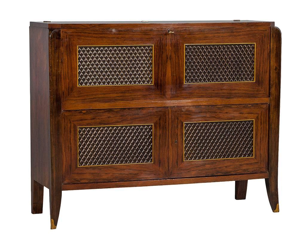 This Art Deco style bar cabinet was designed by Editions AV. Crafted out of rosewood, it has an ivory lacquer interior with brass detailed shelving and storage. The top folds back to be a shelf and the top front fold downs to be a bar prep area