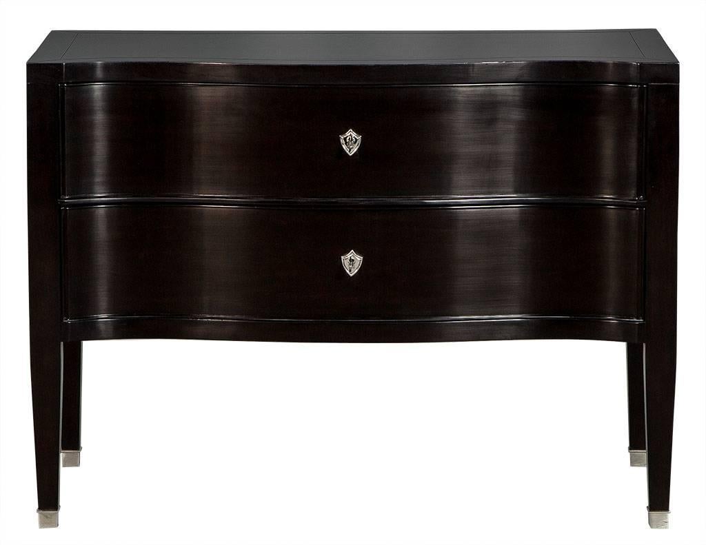 This traditional style chest is a truly Classic piece. It showcases an elegant serpentine front with two drawers and is finished in a rich, black lacquer. Adorned with silver hardware and ferrules on the legs, the inside is finished in ivory for a