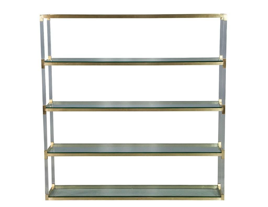 This stunning étagère is ideal for any Mid-Century Modern living space. Alternating brushed brass and Lucite frame supports four clear glass shelves. The clean lines and mixed media of this piece make it not only functional but effortlessly chic.