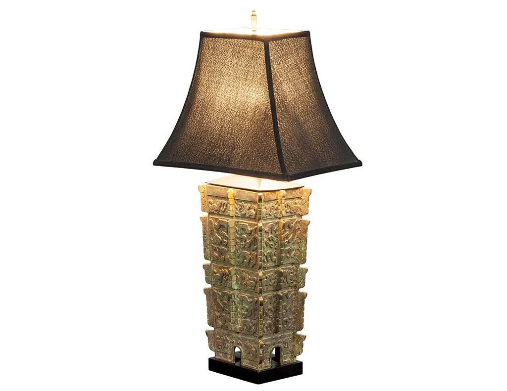 Sculptural bronze lamp covered with oriental style motifs on an ebonized wooden platform. Designed in the style of James Mont.

Measurements listed reflect the profile of the lampshade.

Actual lamp base measures:
W 9
