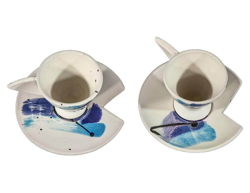 Vintage Postmodern pair of sculpted cup and saucer. With a unique handle cut-out from the saucer. In white with tonal blue and black abstract motifs. Cups signed on bottom as per photos.