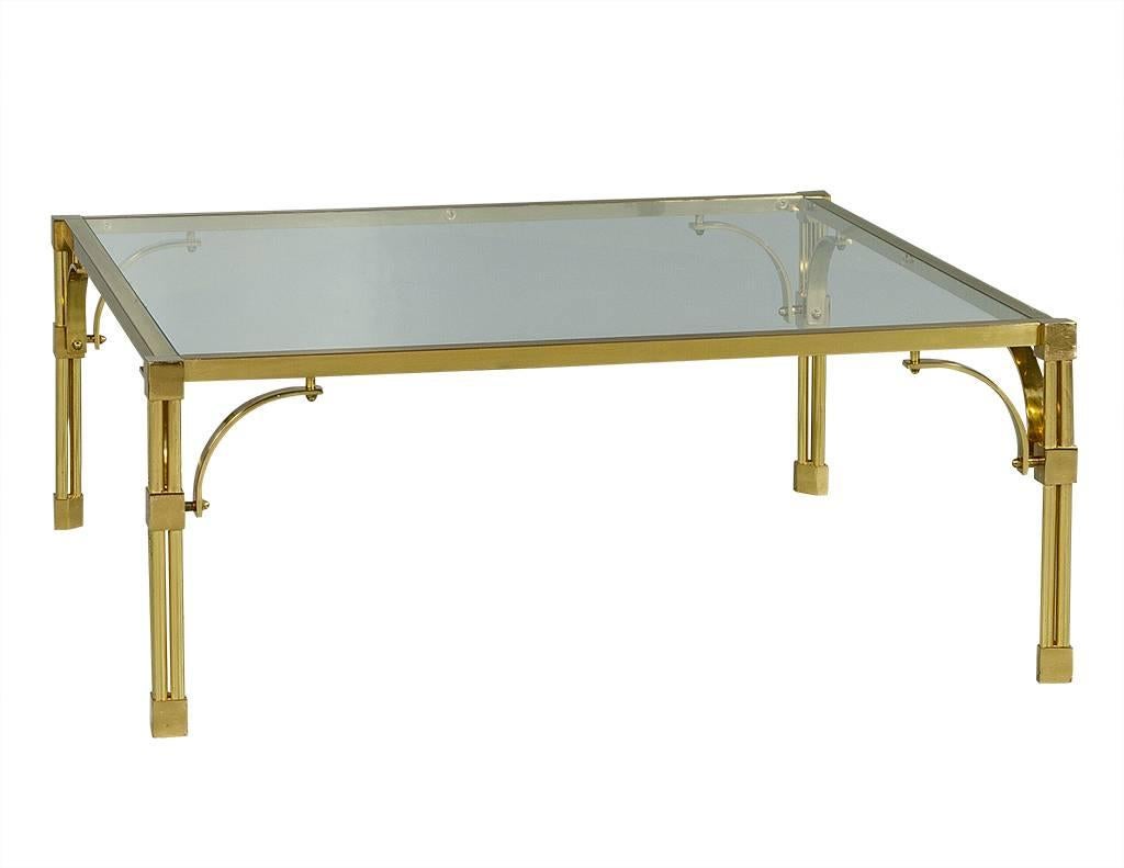This chinoiserie style cocktail table has the perfect amount of detail. The polished brass frame showcases a subtle Asian motif above the tri-column legs, the base of which feature square knuckles. It is topped with a piece of square glass, adding