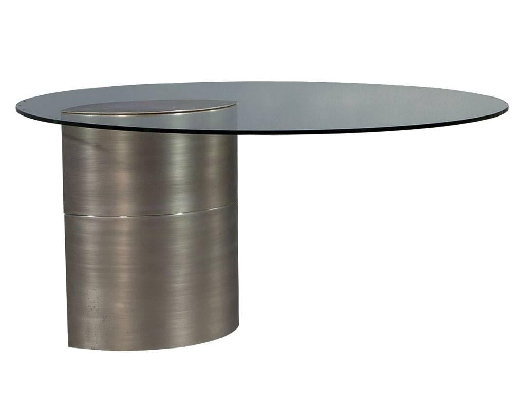Original 1970s design, featuring thick round glass top with a ellipse shaped brushed chrome base, offset to one side. The extreme weight of the pedestal holds the table secure.

Please note shipping charges are quite expensive due to the sheer