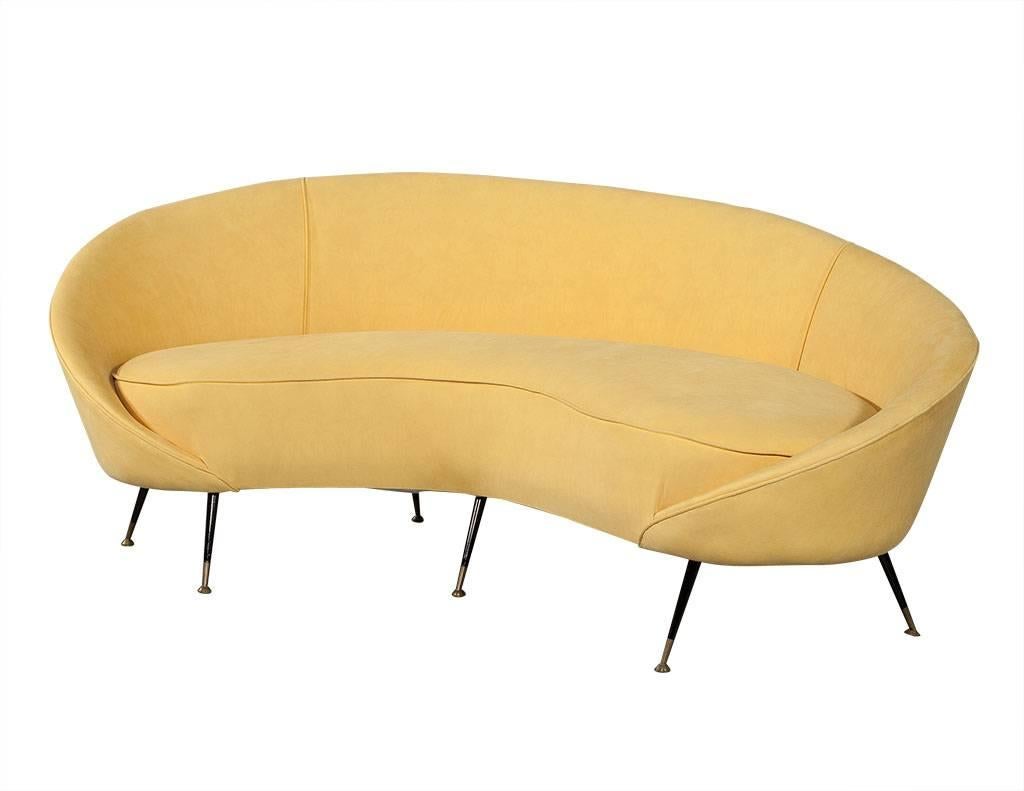 Retro Crescent shaped sofa in manner of Federico Munari. Low curved back with single cushion, upholstered in canary yellow velvet on thin tapered legs with brass feet tips. Matching chair sold separately.