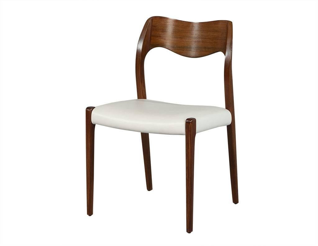Set of four dining chairs with white leather upholstered seats. Curved and carved backrest and uniquely designed arms that extend outwardly, 1951 marked the year Møller designed the #71 chair which became one of his most popular designs. The subtle