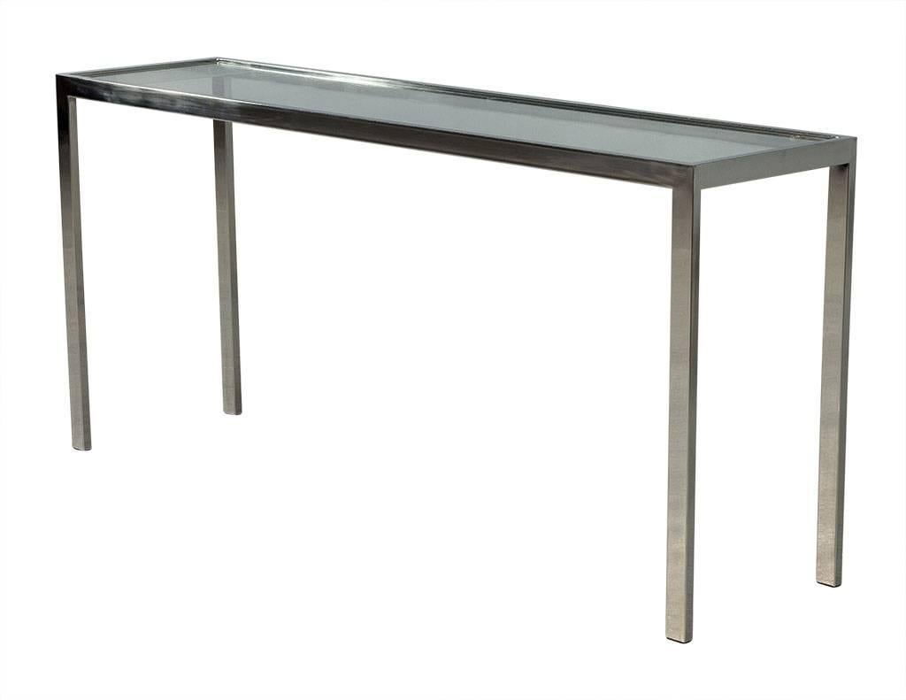 This modern console table is modest yet well designed. It is composed of a chrome frame with inset glass as the top surface. Perfect for a sophisticated home.