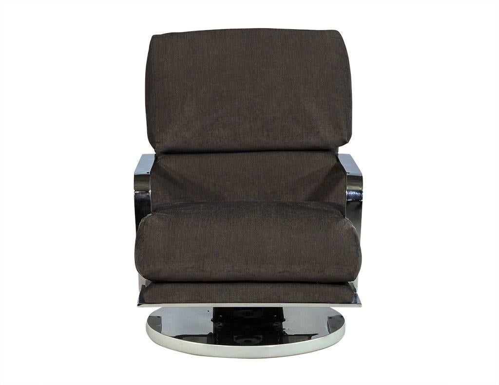 This modern swivel chair sits atop a round, spring base that rotates, with stainless steel armrests and new grey/green cloth fabric upholstery. An interesting piece perfect for a modish home.