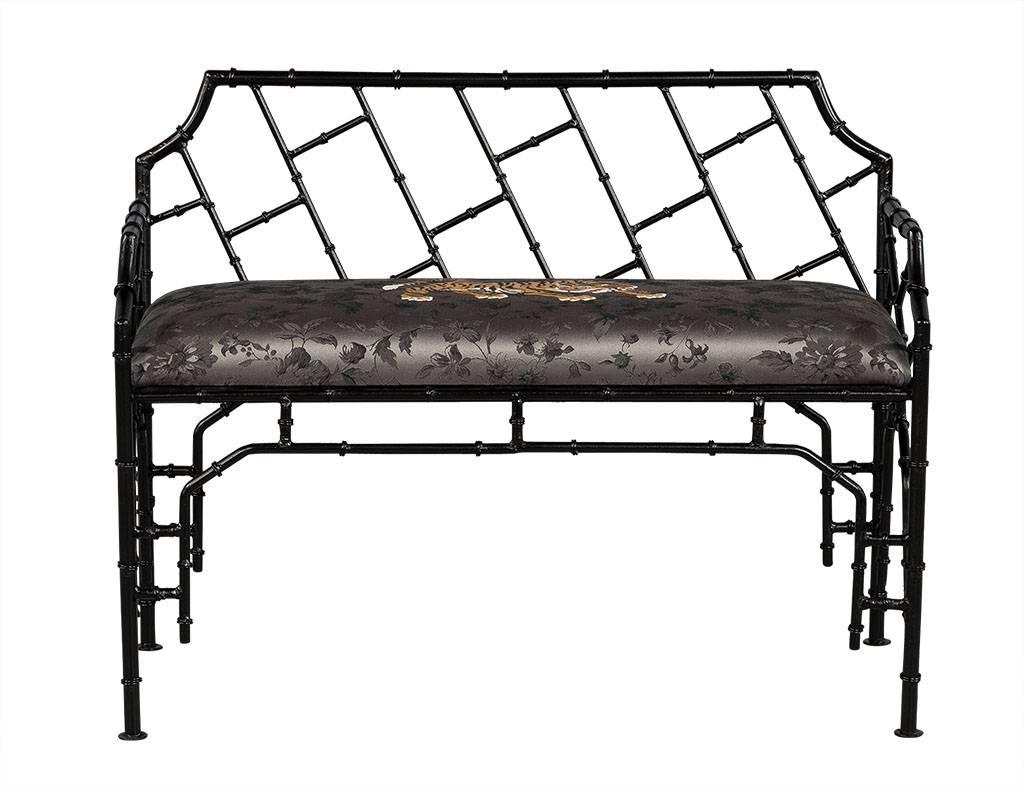 This chinoiserie style bench is a real statement maker. It is newly refinished and upholstered and in excellent condition. The frame and legs are crafted out of black wrought iron with a dark grey satin floral pattern on the bench seat. To add even