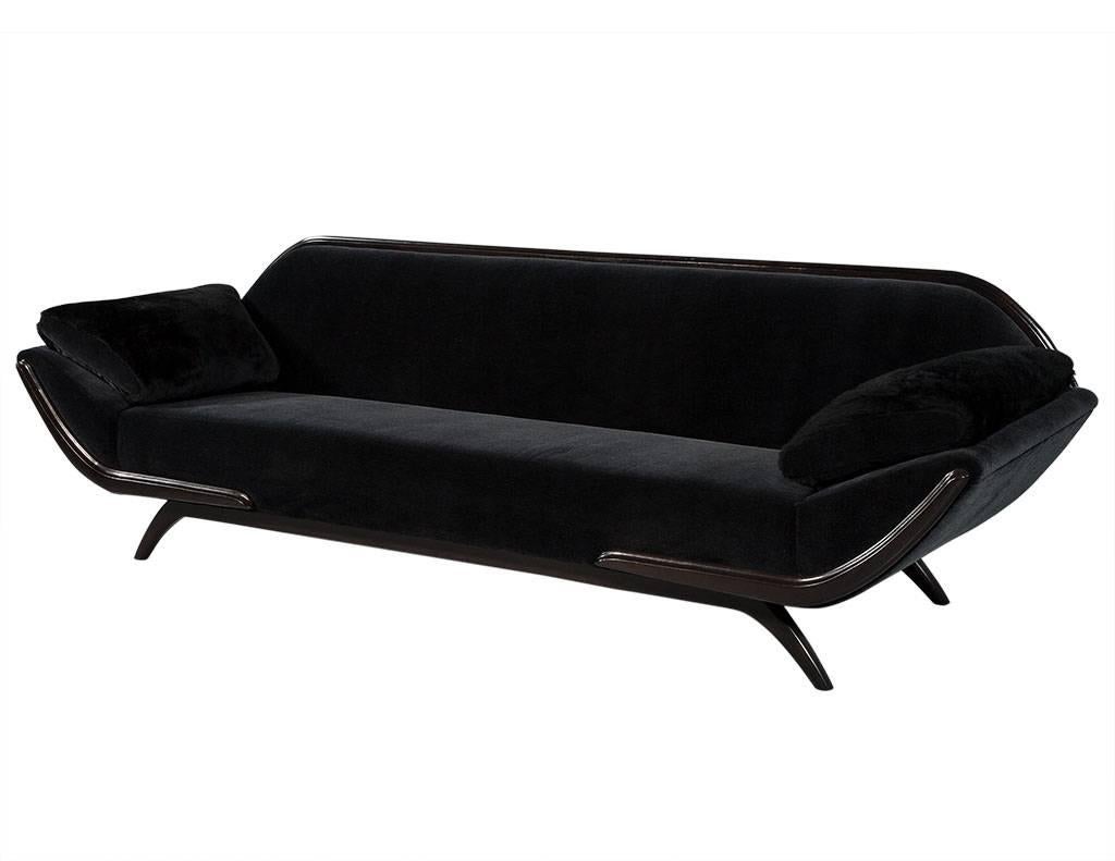 This Mid-Century Modern sofa is absolutely luxurious. It is in excellent restored condition, and is a true representation of 1950s style. The upholstery is a black mohair velvet, while the soft pillow arms are covered in fur. The base, legs, top,