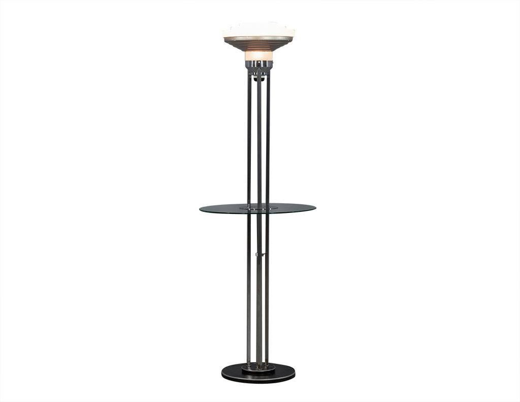 This Art Deco floor lamp hails from France. Absolutely stunning, it has three-ridged glass at the top, a metal piece beneath, and a round glass lamp section under the metal piece. There are three stainless steel rods from the round base to the lamp