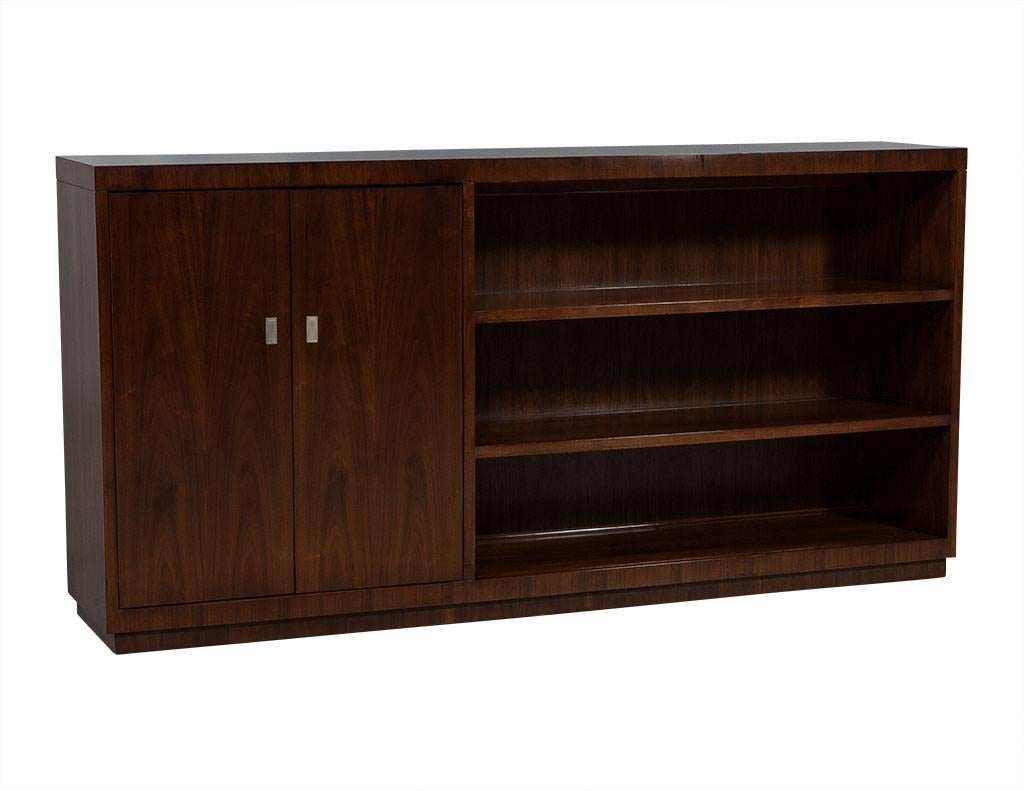 This modern bookcase cabinet has two doors on the left with two shelves and one drawer inside and a right side with three open shelves. An attractive piece perfect for any home.