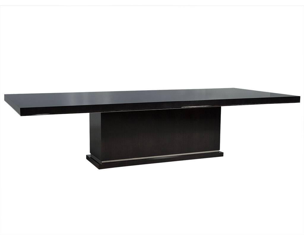 This modern dining table is a Carrocel Custom creation. It is handcrafted out of solid walnut and stained in a deep charcoal black finish, hand polished to a luxurious sheen. The solid base is accented with polished nickel detail, adding just the
