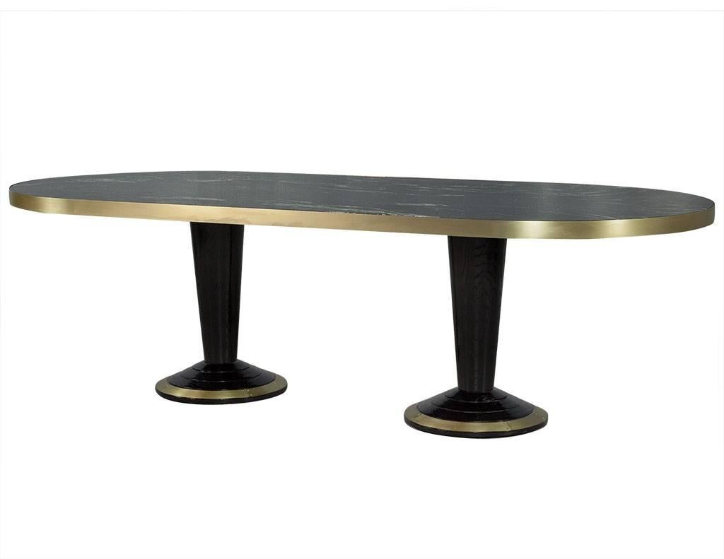 Absolutely stunning black marble top table with white veining details trimmed in a thick brushed brass metal banding. Two wood pedestal bases finished in black and trimmed in matching brass around bottom edges. Please note this table can be made in