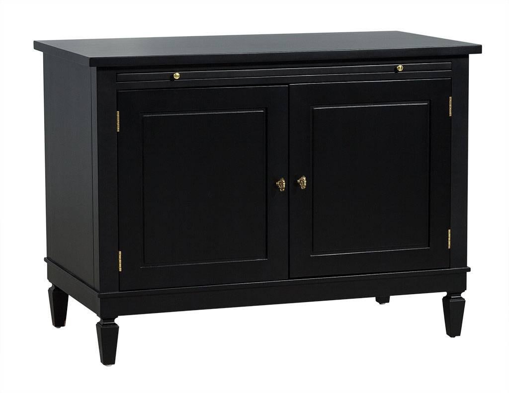 This modern chest is designed by Randall Tysinger. Composed of ebonized wood, the chest contains a pull-out shelf and table with two doors and two shelves inside divided at the centre. The piece is adorned with brass door hinges, doorknobs and knobs