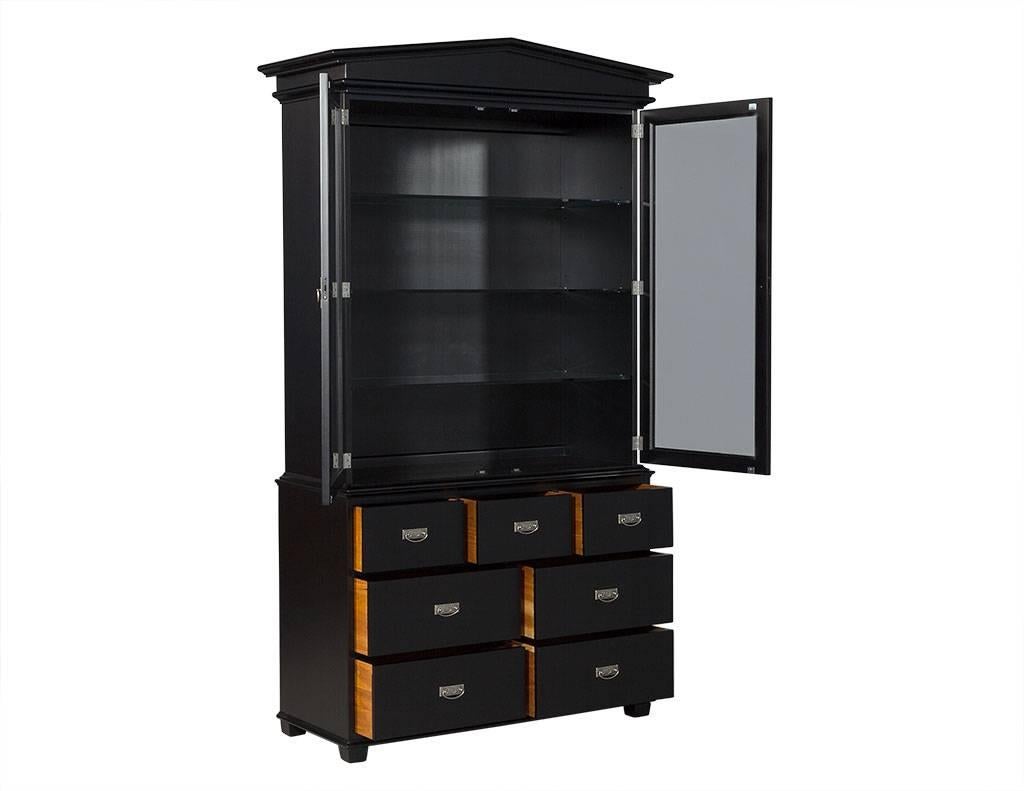 This modern display cabinet is designed by Randal Tysinger. Composed of ebonized wood, the cabinet has a top section with two glass doors and three glass shelves inside with drawers in the bottom section, three on top and two rows of two drawers