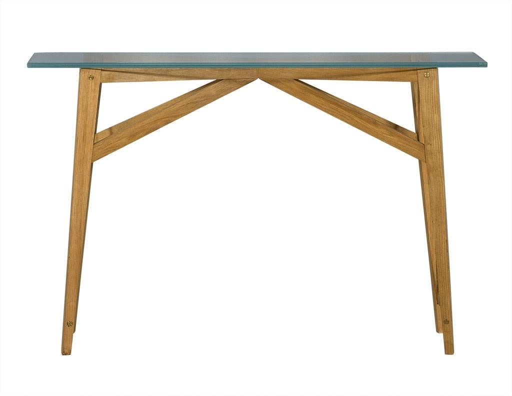 These Mid-Century Modern console tables are uber stylish. The glass tops sit upon light colored wood bases with x-shaped metal supports on the sides. Truly interesting tables, perfect for a trendy home.