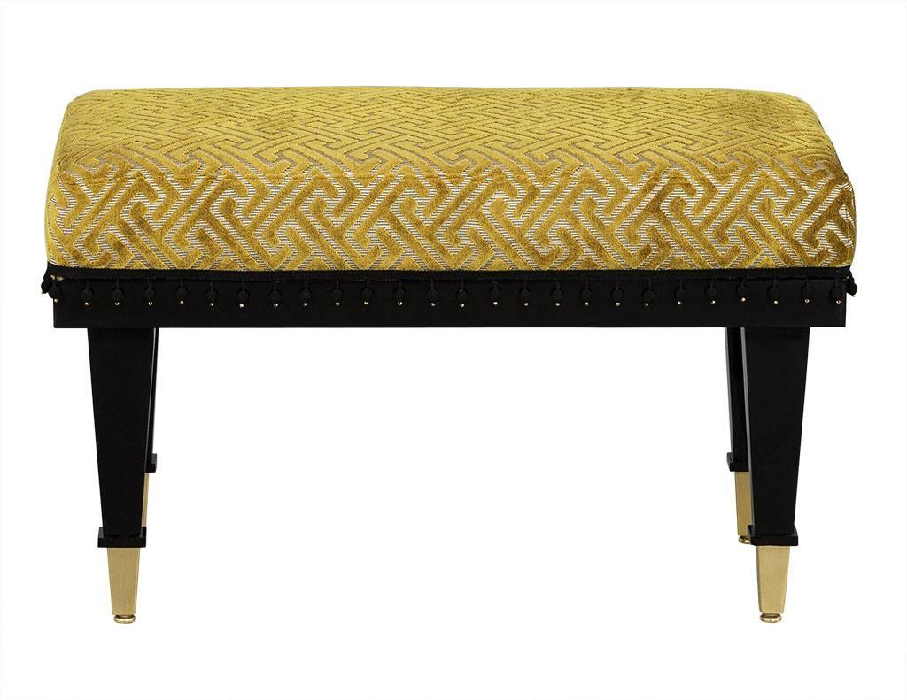 These transitional style benches have black glossy frames are adorned with gold tapered foot caps and topped with a unique chartreuse patterned cut velvet upholstery. The black bobble trim is the flawless finishing touch, making these stools perfect