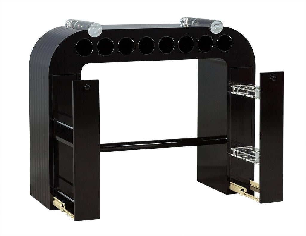This Art Deco console table is truly unique. It is comprised of black laminate with high gloss and matte stripes adorning the top and sides of the piece. There are two Lucite rolls on the top surface, and two tall pullout drawers at each side with