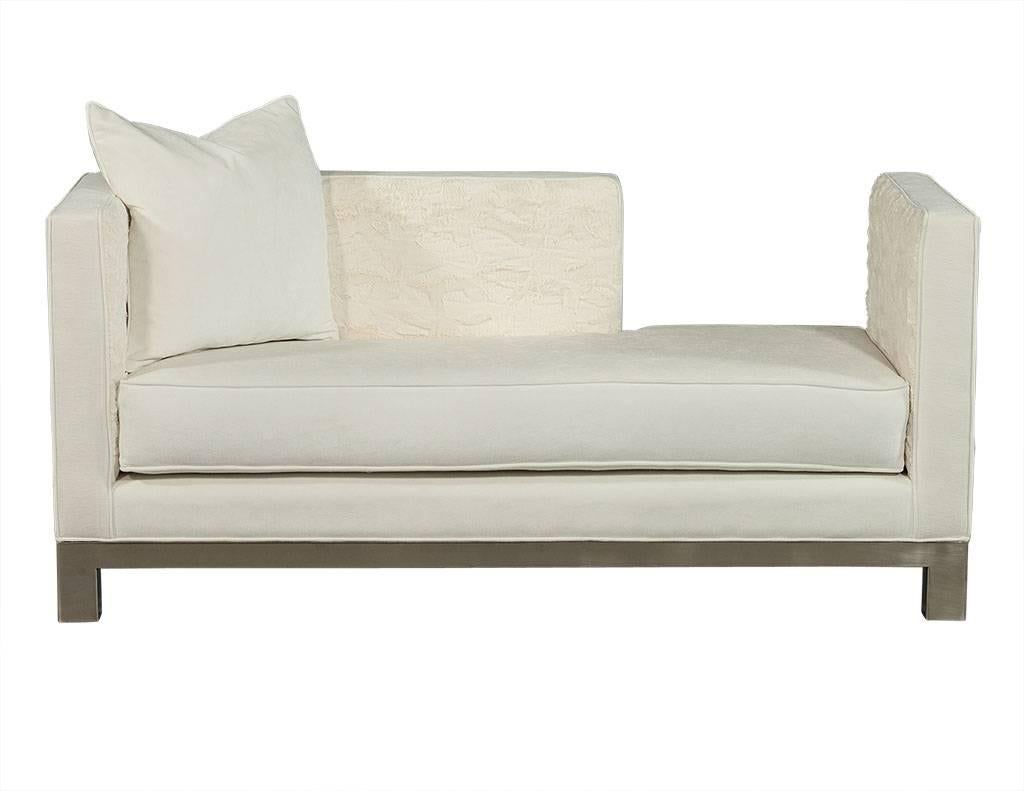 Stunning pair of opposing day bed loungers with a linear shape contrasted by luscious soft white upholstery. The inside panels of the day beds are upholstered in cozy white faux fur and includes a down blend accent cushion. Resting on a brushed