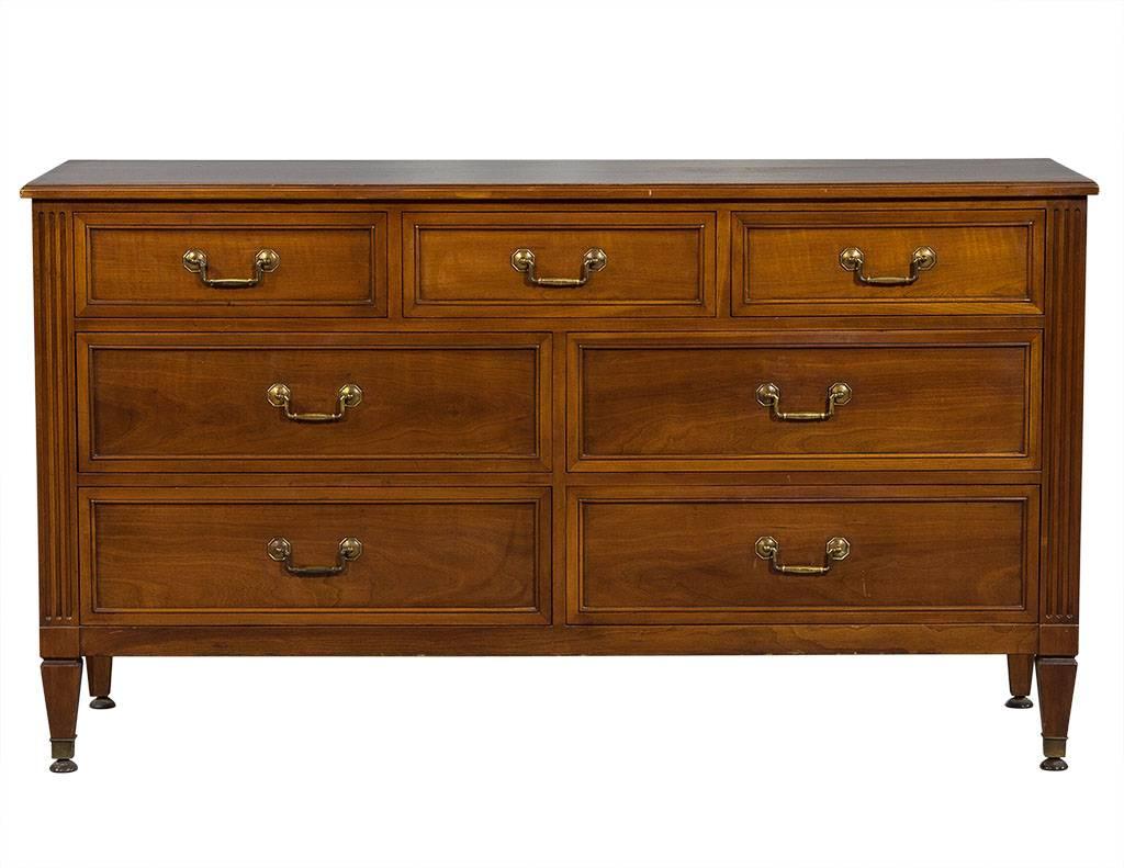 This Louis XVI style dresser is designed by Kindel Furniture Co. It consists of three drawers at the top, two rows of two drawers below, and wooden trays in the top two drawers on each end. A smartly designed piece perfect for a classic home.