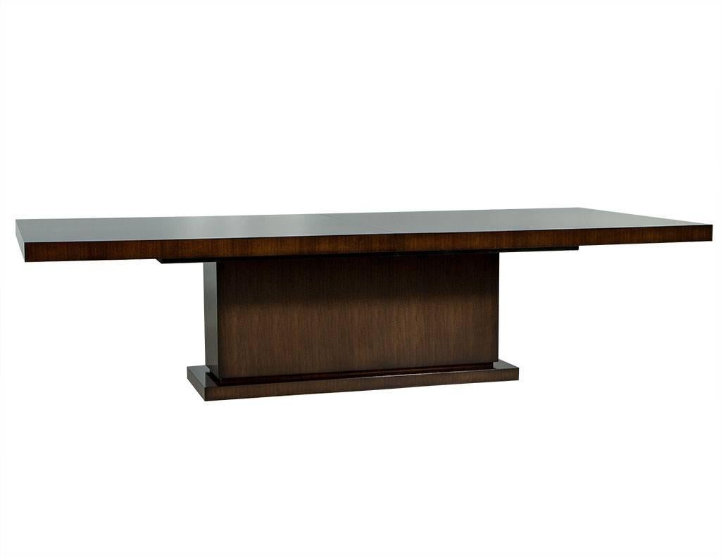 This modern Art Deco style dining table is made to order. Composed of solid walnut, it contains two leaves and sits atop a pedestal base. A neatly designed piece perfect for any dining room. 

This is a custom, made to order table. Lead times