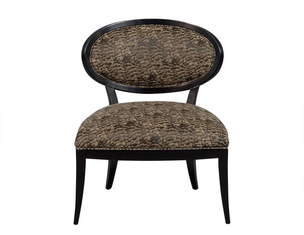 These custom frames from Carrocel offer a wide profile with black show wood and oval backrest. Seat and backrest are upholstered in light metallic brown and black patterned fabric.