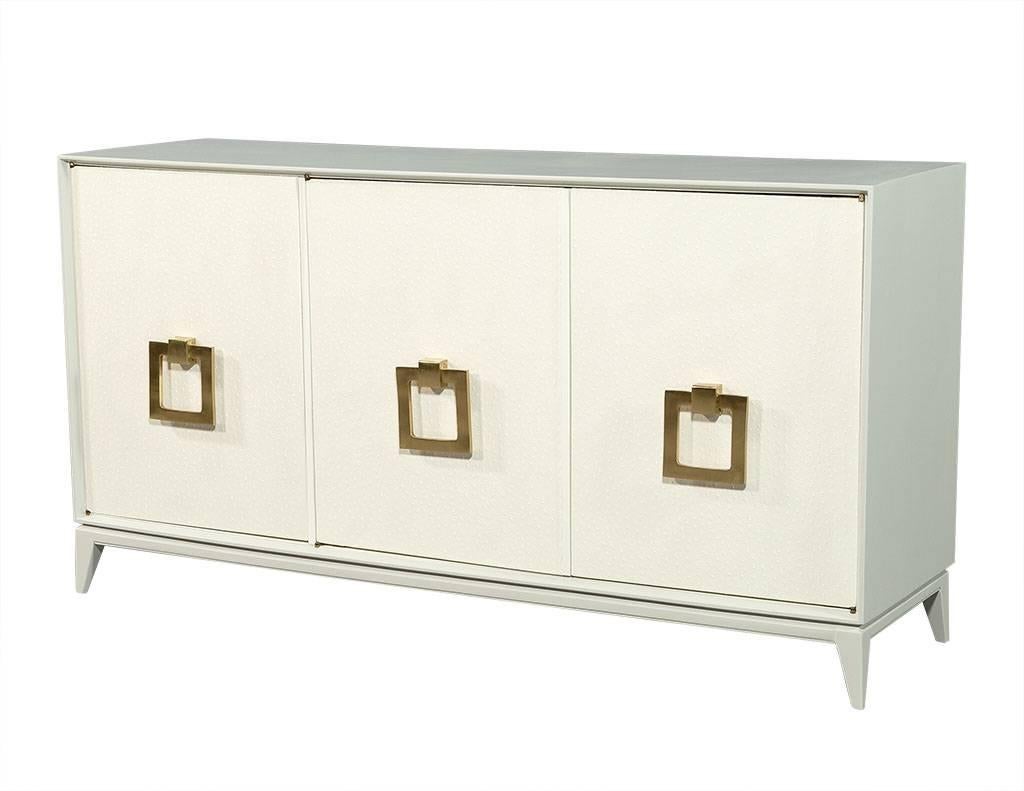 This 1940s buffet is a Carrocel original and excellently restored. It is wrapped in a faux ostrich upholstery and finished in a light grey. The doors are also wrapped in the upholstery, and are adorned with custom brass hardware. A beautiful piece