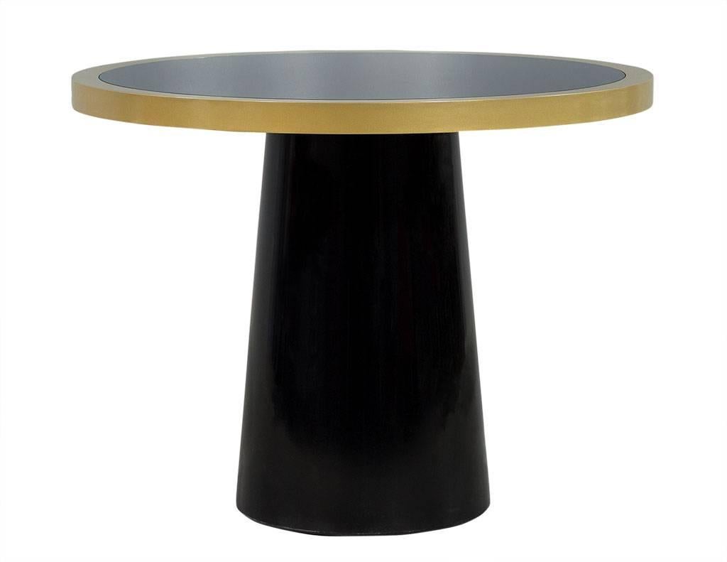 This made to order foyer table is part of the Carrocel custom collection. The base is crafted out of solid hand polished black lacquer and is geometric in shape. The tabletop is a black glass inset piece surrounded by a brass ring, adding more depth