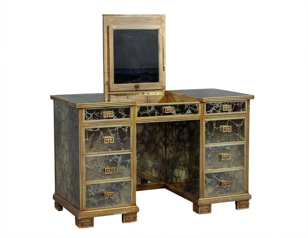 This contemporary makeup table is super unique. The vanity, top, front, and sides are covered in antique mirror with antique gold finish wood edges and drawer handles. The piece has a hinged flip up vanity mirror in the centre with a mirror inside
