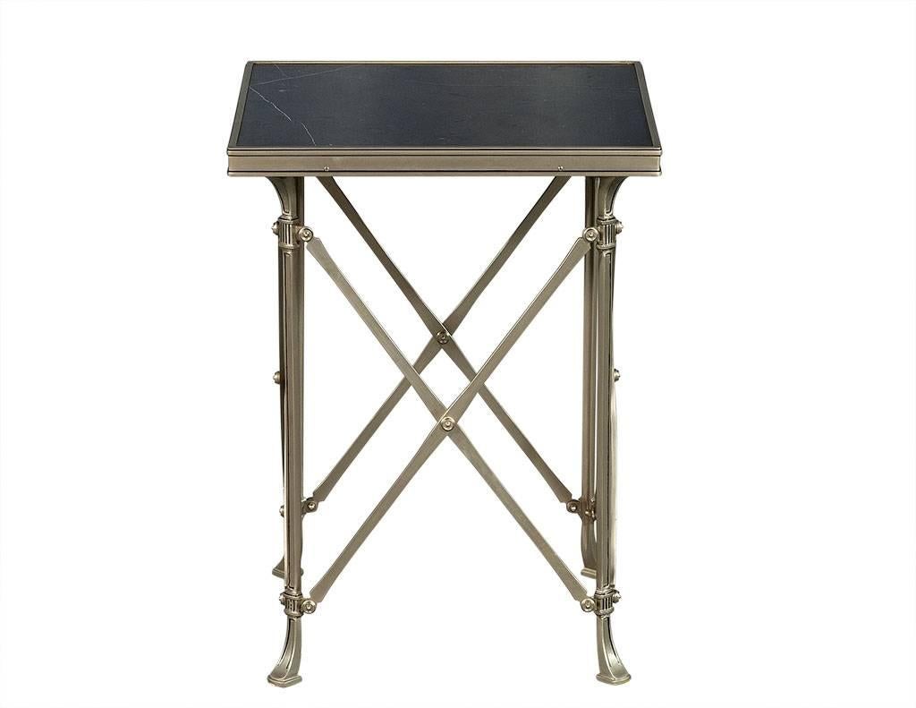 This neoclassic Gueridon is original and in very good condition.  The square, black marble top has silver metal edges and a base with x-shaped connections between the legs with curved detail at the top and feet of the legs.  A beautiful piece
