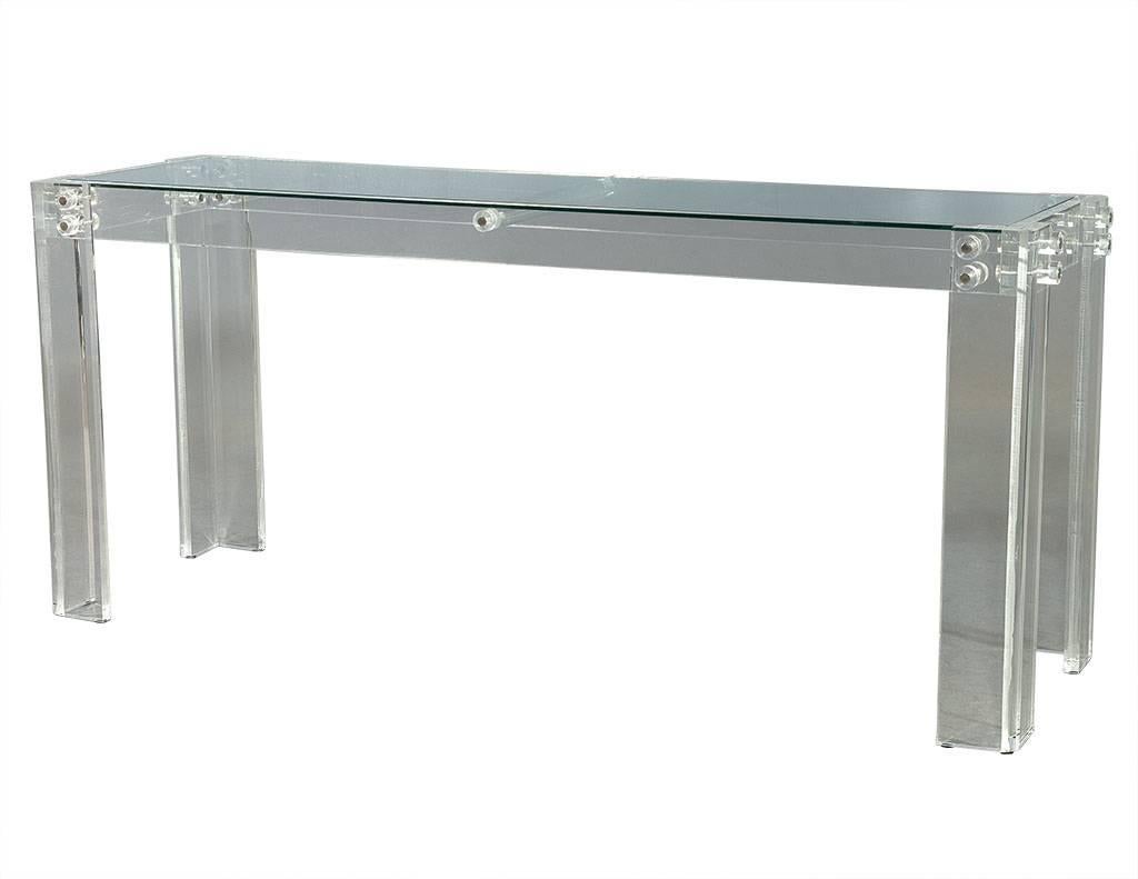 This ultra-modern console table is crafted out of acrylic with a glass top and metal connector screws, as well as a Lucite dowel connector in the center top beneath the glass.  A simple yet beautiful piece, perfect for a contemporary home.