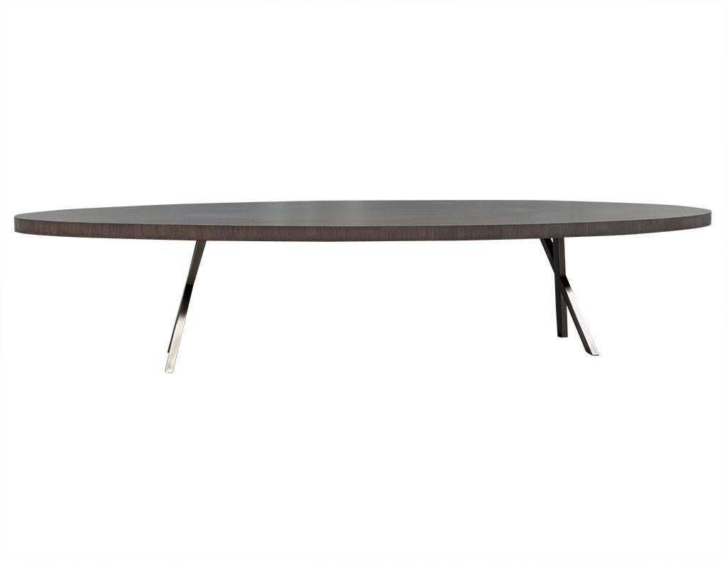 This sleek dining table has a rift walnut top positioned on a pair of handmade stainless-steel bases, with a hand-rubbed natural grey finish on the legs and tabletop. An interesting piece perfect for an edgy dining room. This piece is made to order.
