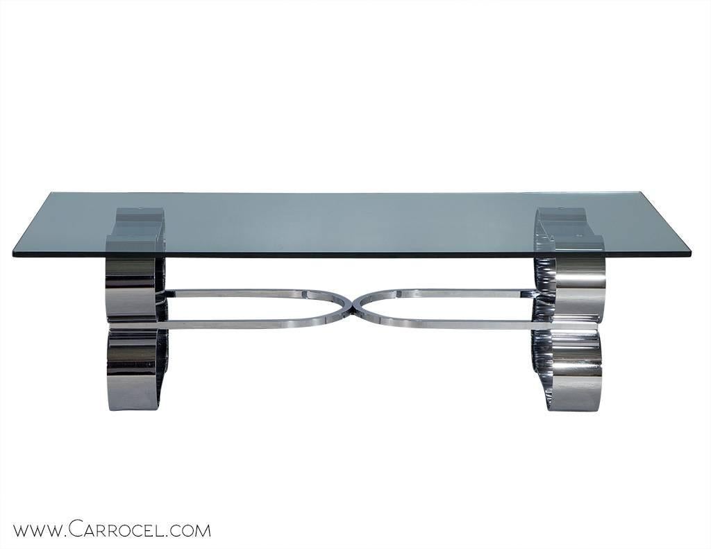 Gorgeous post modern coffee table. Features a unique design with an interesting stainless steel base and thick polished edge glass top. It has a bold presence that enhances the space it lives in. 