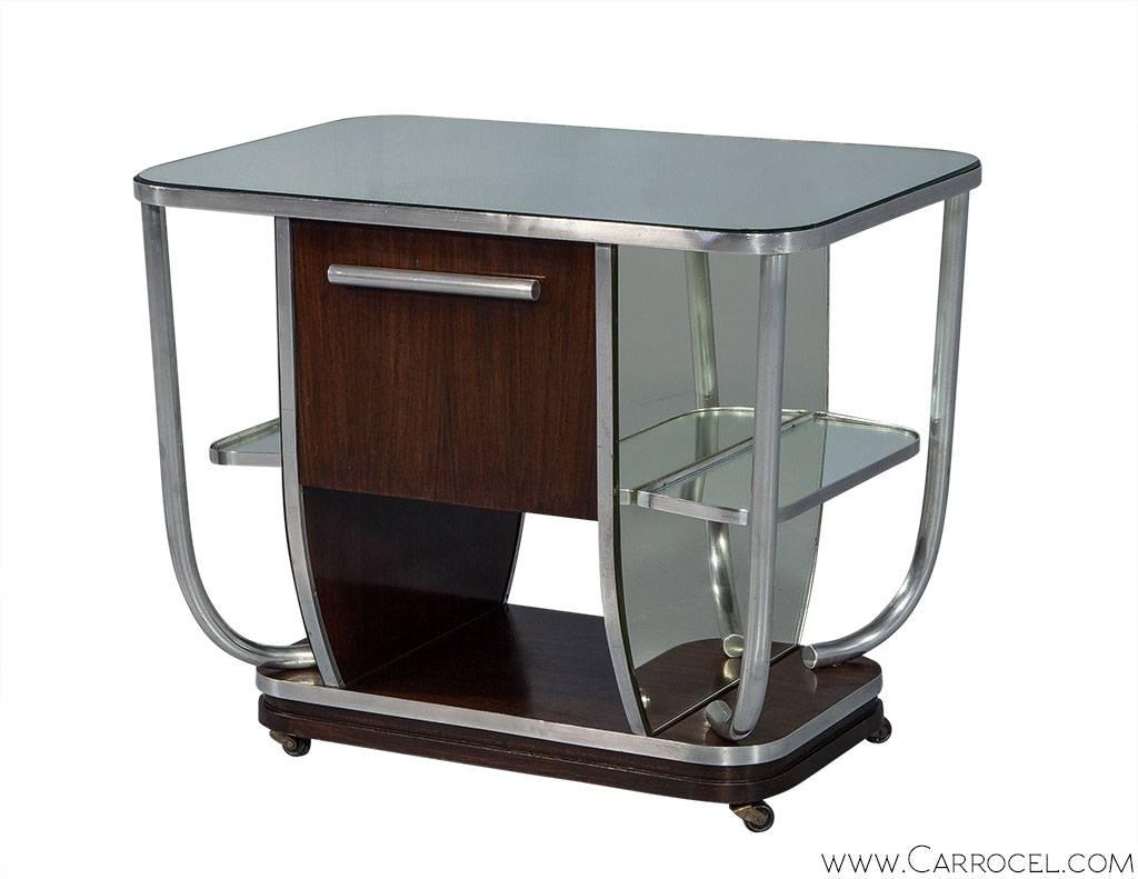 A gorgeous original piece straight from the Bauhaus era with undertones of Art Deco influence. The same on both sides, the bar has a drop down door concealing a central compartment, a lower open cubby. The top of the bra is mirrored, trimmed in
