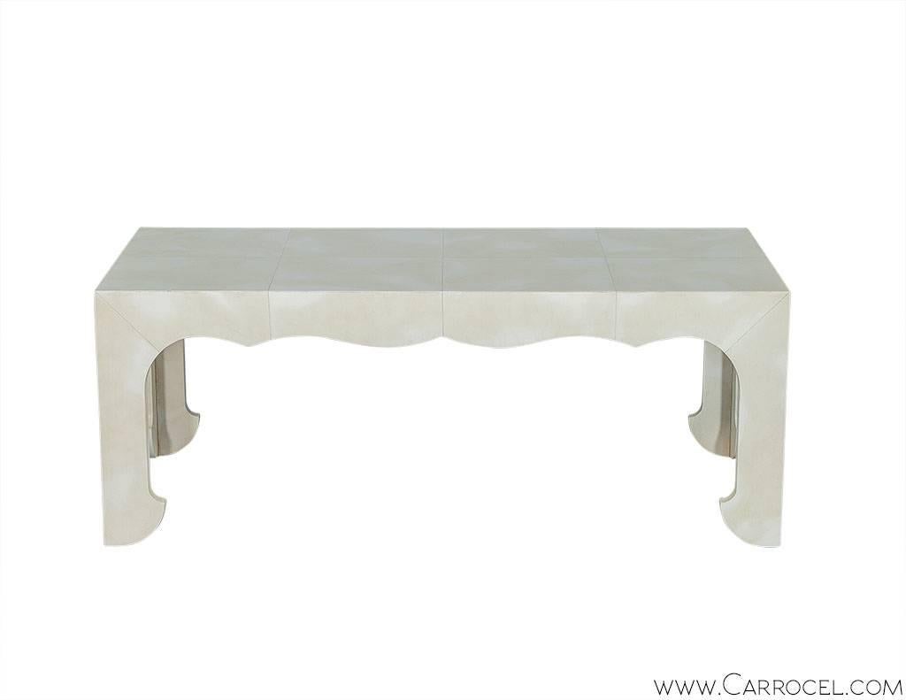 Gorgeous cocktail table from Hickory White features a modern design with hints of Moorish influence visible in the scalloped shape. With otherwise clean lines and edges the table in finished in a vellum parchment giving a cloudy effect to the