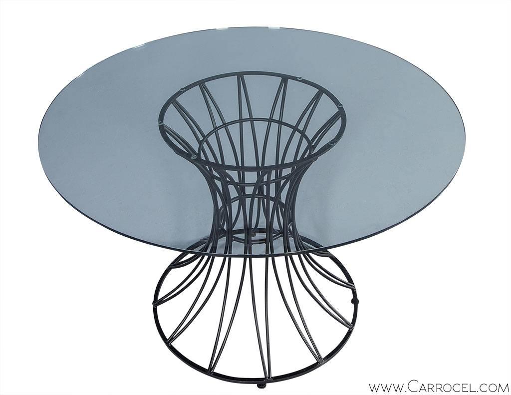 This table is designed to highlight its gorgeous black iron base, as round glass top rested over an elegant geometric base. Constructed with an open design, a star burst pattern forms vertically over an hourglass shape. Perfect proportions and an