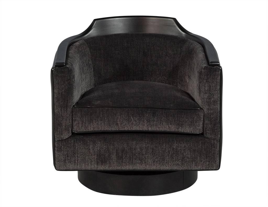 This Mid-Century Modern tub chair is plush yet sophisticated. It sits atop a black wood, rounded base that rotates a full 360 degrees and is upholstered in luxurious dark charcoal fabric. The sides and back are composed of black leather, and black