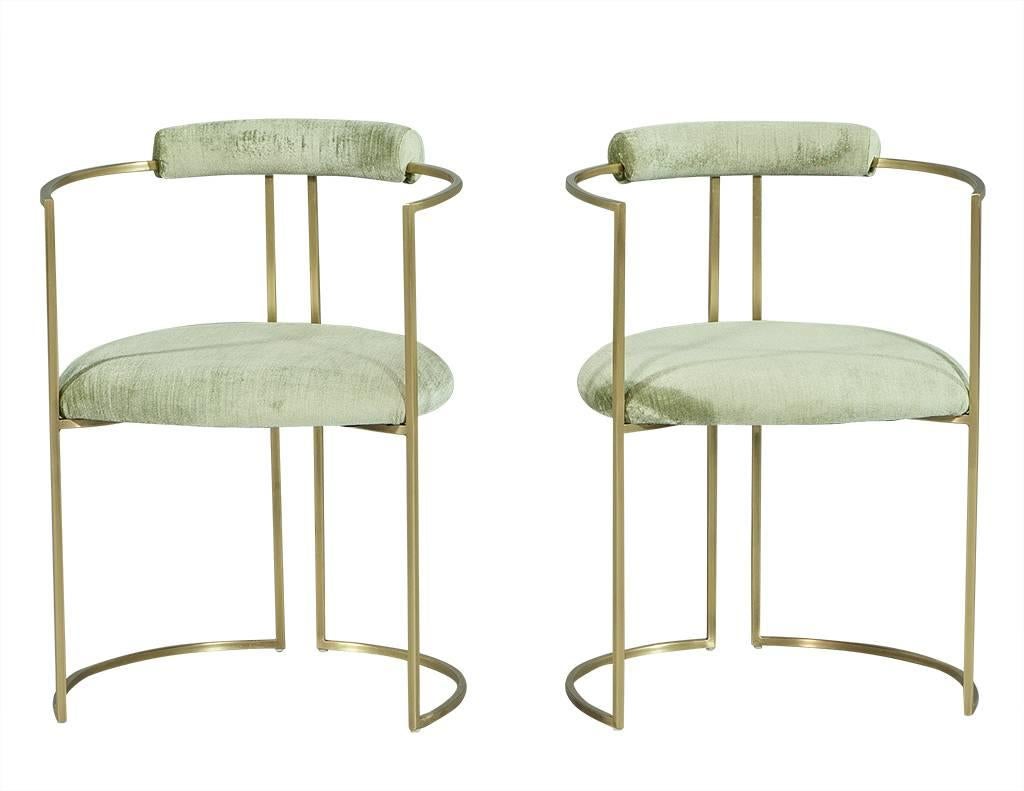 These modern armchairs are part of the Carrocel custom collection. They are composed of a slim, demilune, satin brass frame with a bolster roll on the chair back and rounded seat upholstered in commercial grade sea foam velvet. They make you think