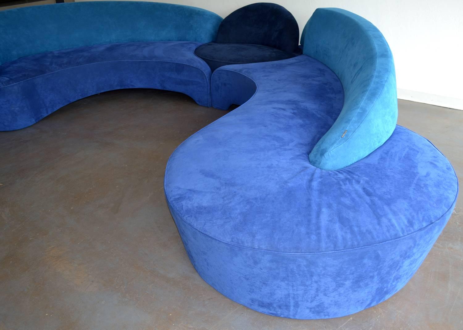 Two rare asymmetric 'Comete' sofas with central circular ottoman designed by Vladimir Kagan for Roche Bobois, 2003. Suede upholstery in shades of azure, navy and royal blue. Two large sections pivot the ottoman to form an 18-foot sofa. Imported from