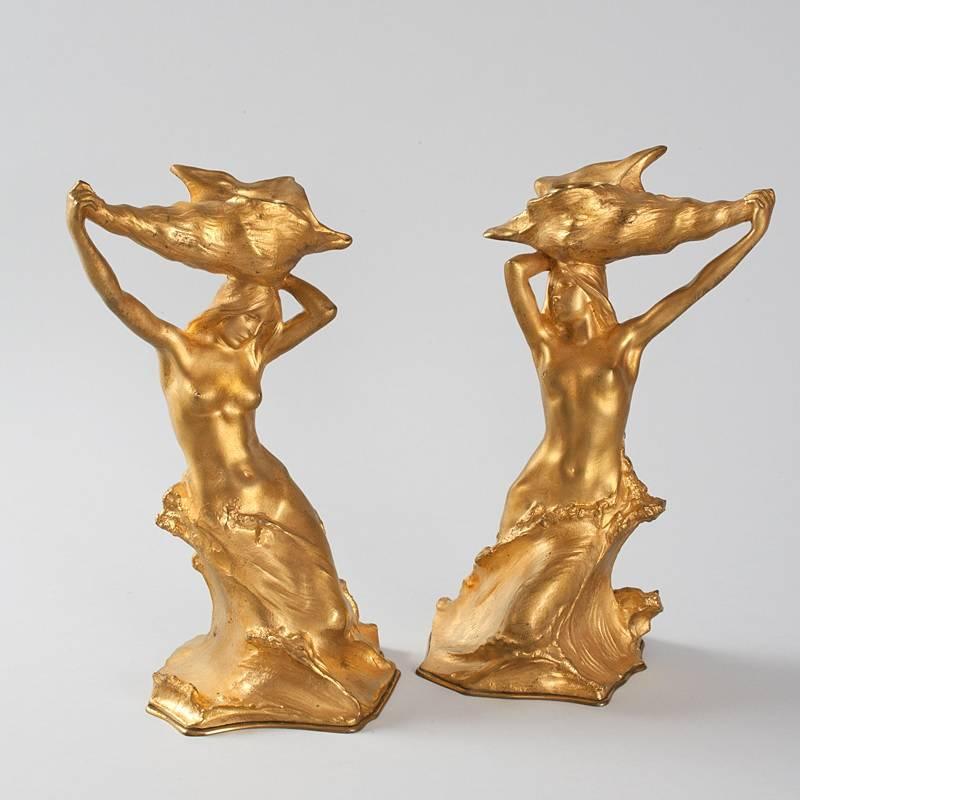 A pair of French Art Nouveau gilt bronze candlesticks by Hans Muller. Each candlestick depicts a nude female figure emerging from the sea, holding a large seashell above her head. Circa 1900.

Signed, ''H. Muller''. 

(MG #14534)