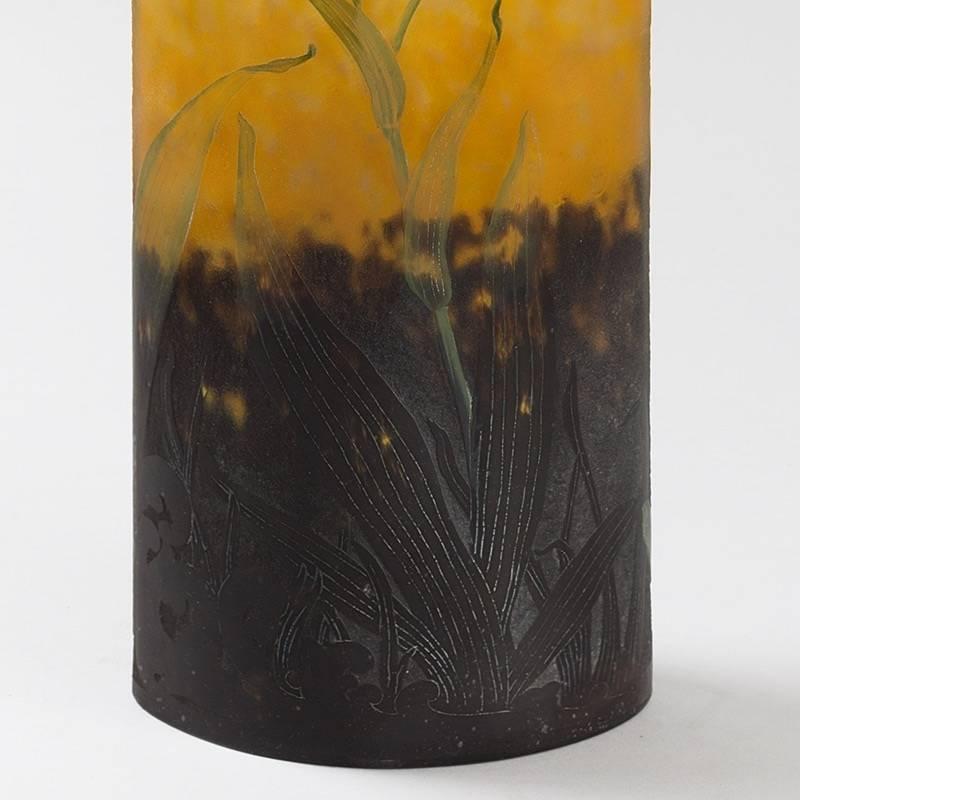 This brightly enameled and etched glass vase by Daum Nancy is the form of an elliptic cylinder, a shape which the designers used specifically because it lends itself to undulating and soft natural scenes, such as this floral landscape. This Art